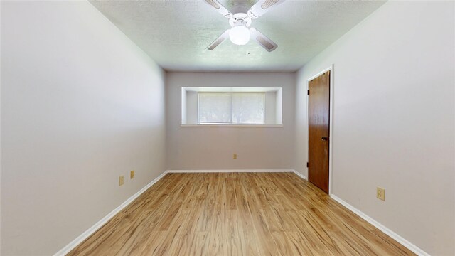 unfurnished room featuring baseboards, a ceiling fan, light wood-type flooring, and a textured ceiling
