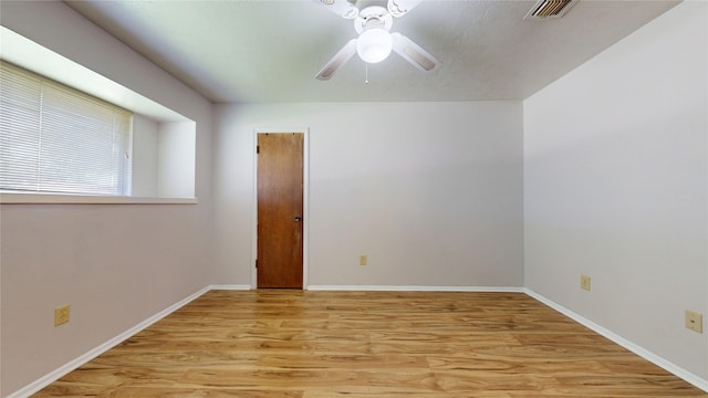 empty room featuring baseboards, ceiling fan, light wood-style flooring, and visible vents