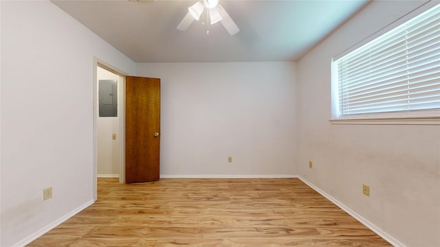 spare room with light wood-style floors, baseboards, electric panel, and a ceiling fan