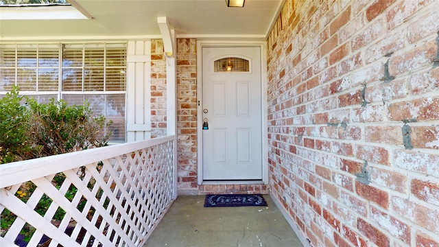 doorway to property with covered porch and brick siding