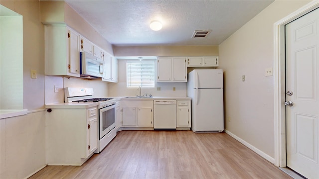 kitchen featuring light wood-type flooring, a sink, white appliances, and light countertops