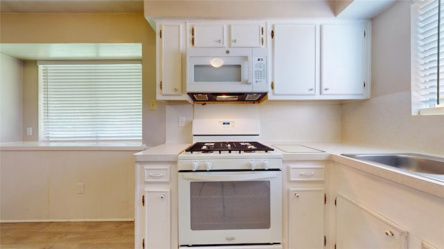 kitchen with white appliances, white cabinetry, light wood-style floors, and light countertops
