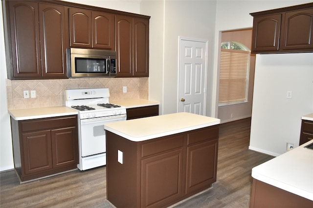 11111 Sprucedale Ct, Houston, TX 77070 - kitchen with decorative backsplash, white gas stove, light countertops, stainless steel microwave, and dark wood finished floors