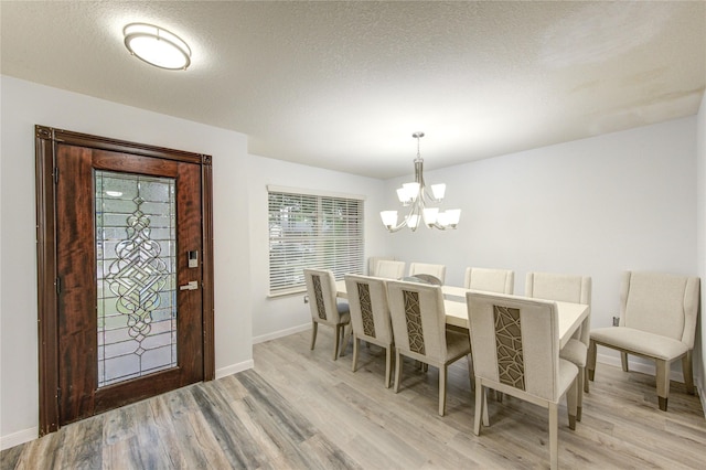10338 E Summit Canyon Dr, Houston, TX 77095 - dining area featuring an inviting chandelier, a textured ceiling, light wood-style floors, and baseboards