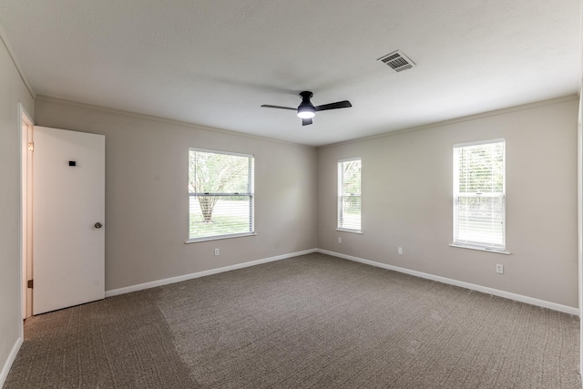 carpeted empty room with baseboards, ornamental molding, ceiling fan, and visible vents