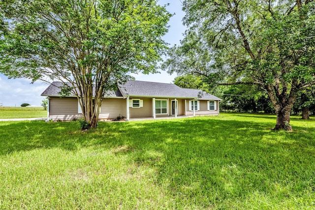 view of front of home featuring a front lawn, a patio area, and roof with shingles