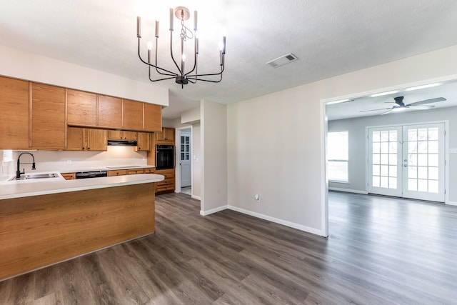 kitchen with visible vents, dark wood-style flooring, brown cabinets, a sink, and black appliances