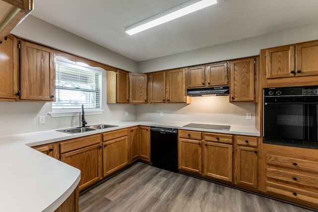 kitchen with a sink, range hood, black appliances, and brown cabinets