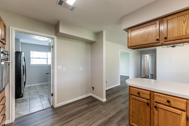 kitchen featuring visible vents, baseboards, light countertops, brown cabinets, and appliances with stainless steel finishes