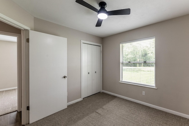 unfurnished bedroom with a closet, carpet flooring, baseboards, and ceiling fan