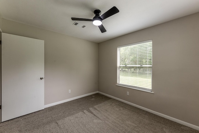 carpeted spare room with ceiling fan, visible vents, and baseboards