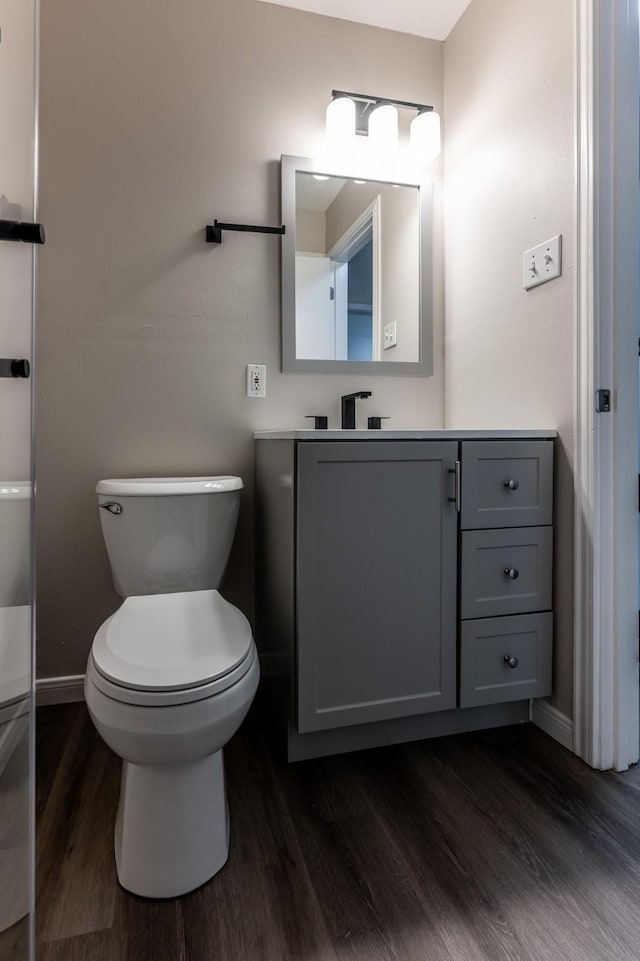 bathroom with toilet, baseboards, wood finished floors, and vanity