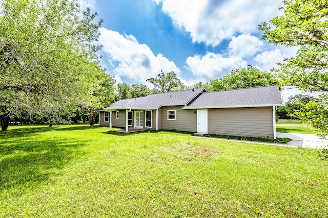 back of property with a lawn, a patio, and roof with shingles