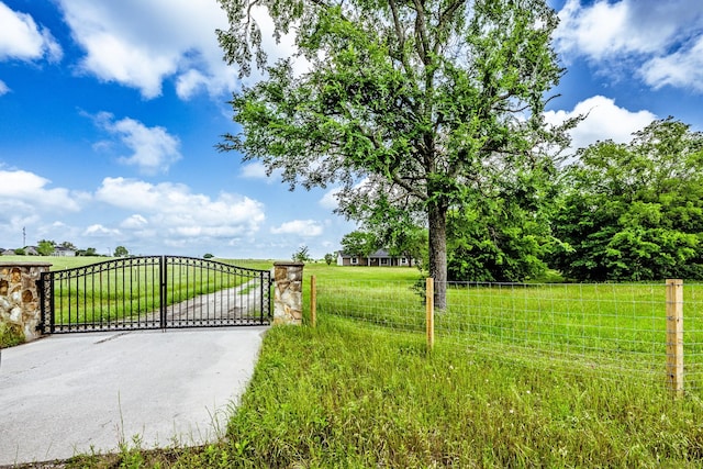 view of gate with a lawn and a rural view