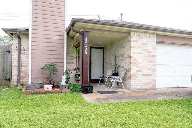property entrance featuring a lawn, brick siding, an attached garage, and fence