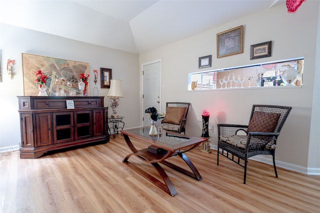 sitting room with baseboards, lofted ceiling, and light wood-type flooring