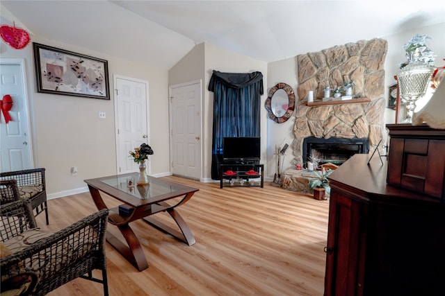living room with baseboards, vaulted ceiling, light wood finished floors, and a fireplace