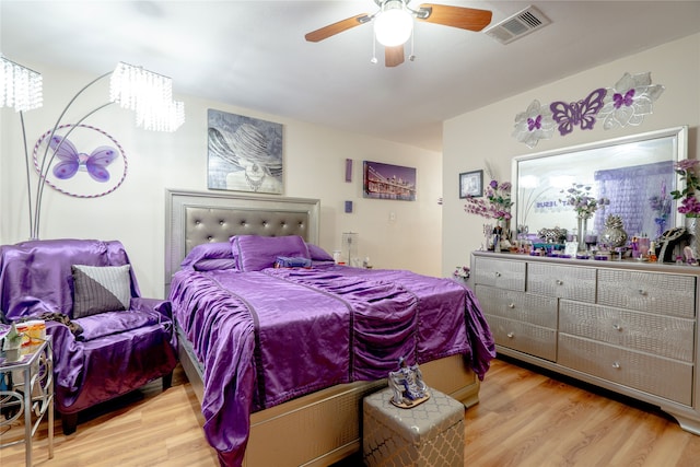 bedroom with a ceiling fan, wood finished floors, and visible vents