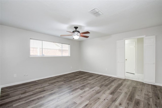 spare room with visible vents, baseboards, ceiling fan, and wood finished floors