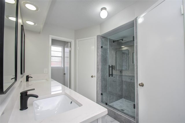 bathroom featuring double vanity, a shower stall, and a sink