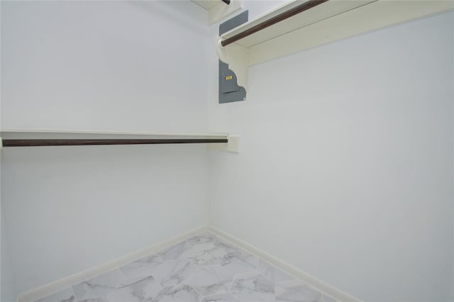 walk in closet featuring marble finish floor