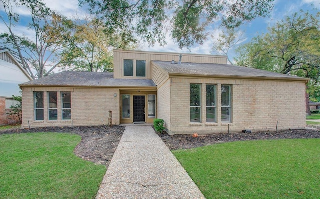 view of front facade with brick siding and a front yard