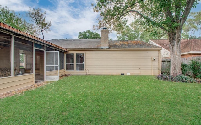 back of property with a lawn, a chimney, and a sunroom