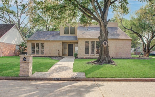 view of front facade with brick siding and a front yard