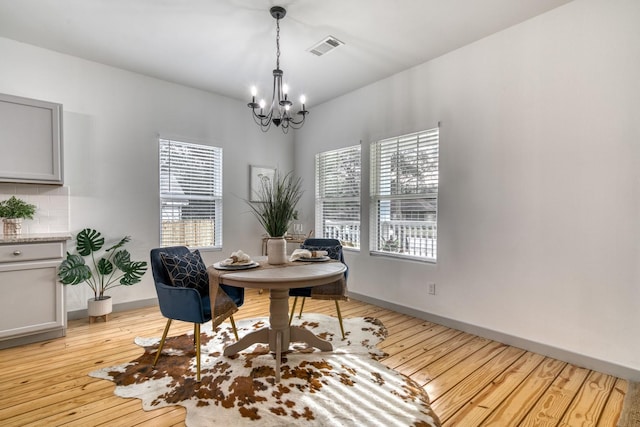 dining space featuring light wood-style floors, baseboards, a chandelier, and visible vents