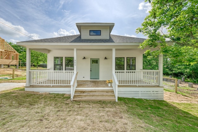 bungalow-style house featuring covered porch, a shingled roof, and a front yard