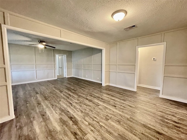1827 Neuman St, La Marque, TX 77568 - spare room featuring a ceiling fan, a textured ceiling, visible vents, wood finished floors, and a decorative wall