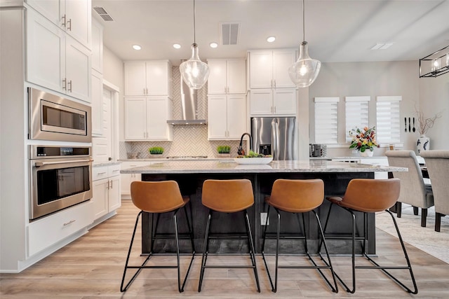 kitchen featuring backsplash, stainless steel appliances, white cabinetry, and visible vents