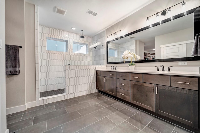 bathroom featuring visible vents, a sink, a walk in shower, and double vanity