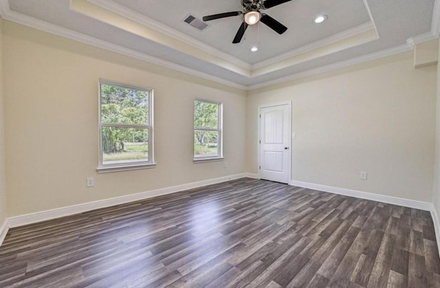 spare room with a tray ceiling, dark wood-type flooring, a ceiling fan, and ornamental molding