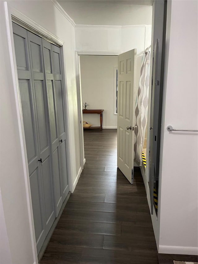 hallway with dark wood-style floors, baseboards, and ornamental molding