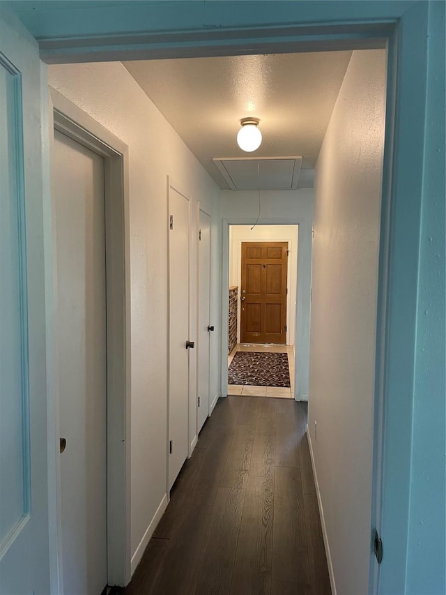 hall with attic access, dark wood finished floors, and baseboards