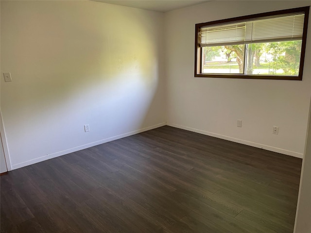 unfurnished room with baseboards and dark wood-type flooring