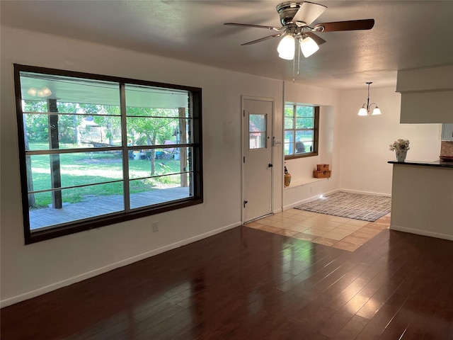 foyer entrance featuring a ceiling fan, wood finished floors, a chandelier, and baseboards