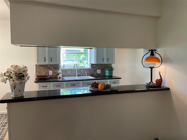 kitchen featuring a sink, tasteful backsplash, and dark countertops