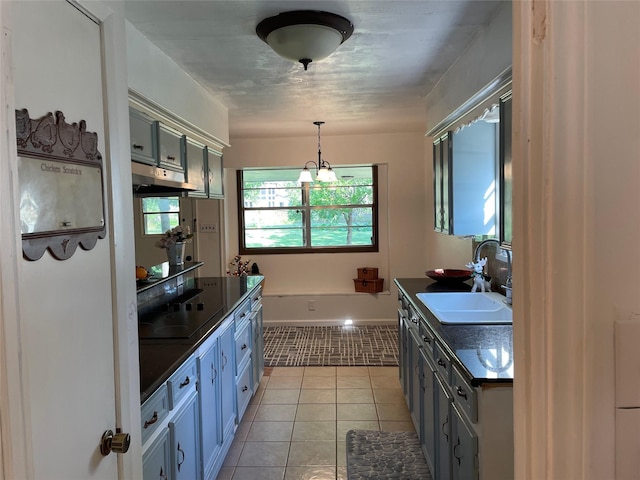 kitchen featuring dark countertops, a sink, light tile patterned floors, black electric cooktop, and pendant lighting