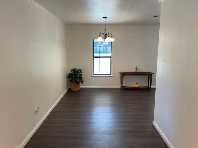 unfurnished dining area featuring dark wood-type flooring, a chandelier, baseboards, and crown molding