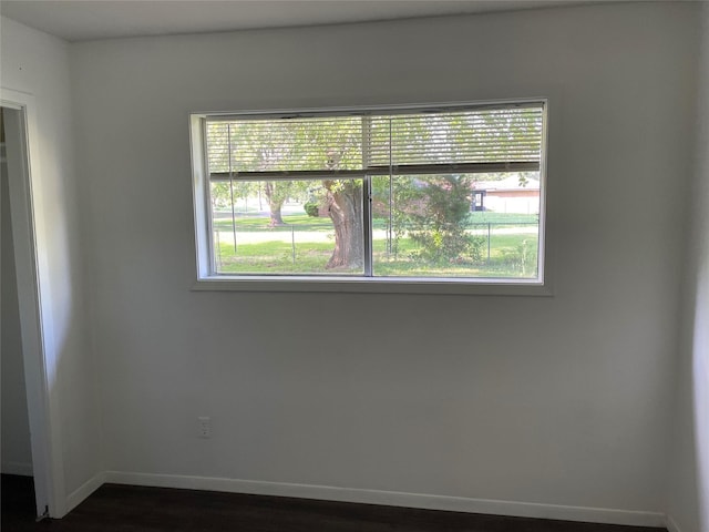 spare room featuring baseboards and dark wood finished floors