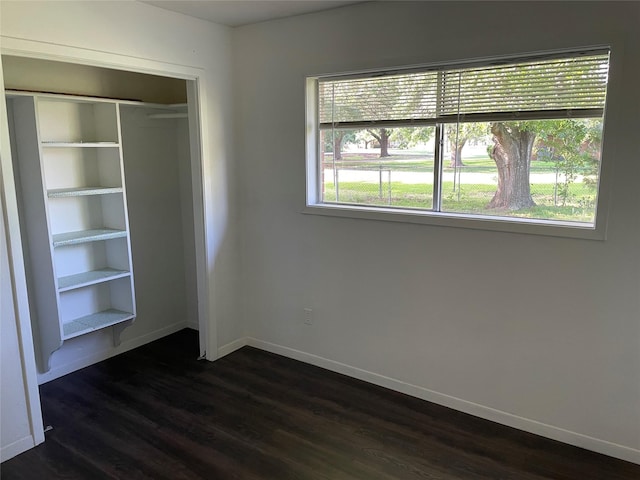 unfurnished bedroom featuring baseboards, dark wood finished floors, and a closet