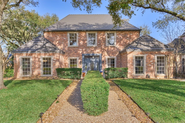 colonial-style house featuring brick siding, a high end roof, and a front yard