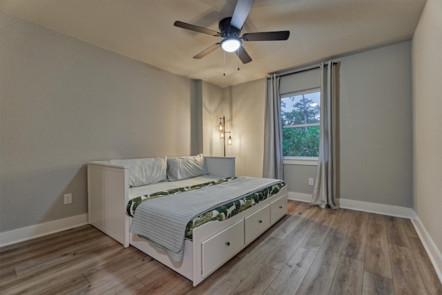 bedroom featuring wood finished floors, baseboards, and ceiling fan