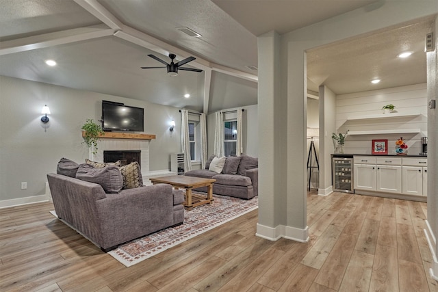 living room with beverage cooler, a fireplace, baseboards, light wood finished floors, and recessed lighting