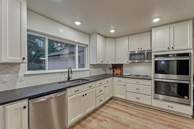kitchen with appliances with stainless steel finishes, a sink, dark countertops, decorative backsplash, and recessed lighting