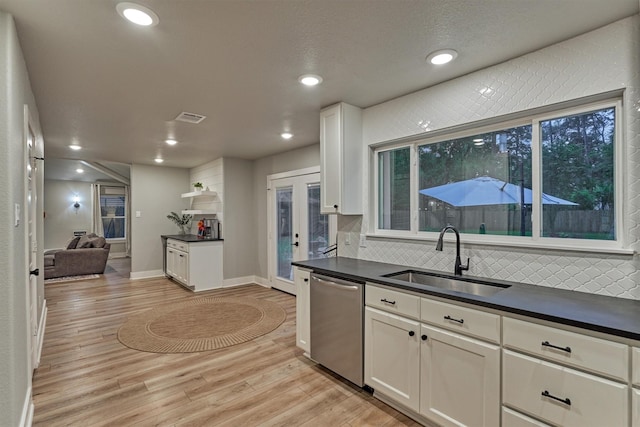 kitchen with a sink, dishwasher, dark countertops, light wood-style flooring, and recessed lighting