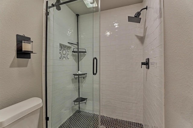 full bath featuring a shower stall, toilet, and a textured wall