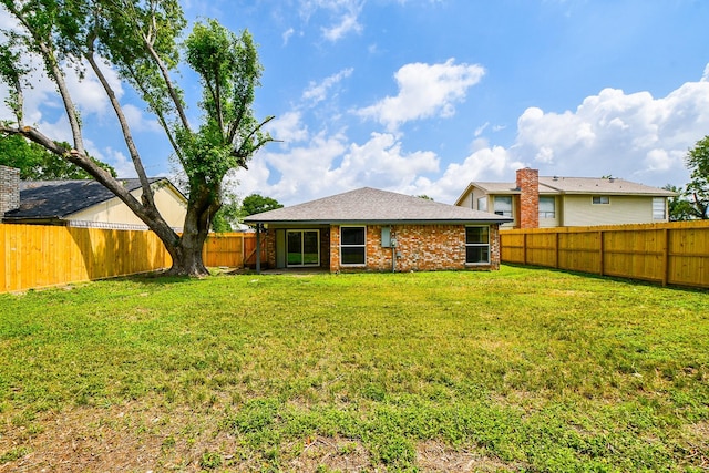 rear view of property featuring a fenced backyard and a yard